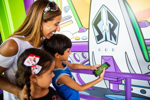 Mom with kids playing Play Disney app in line