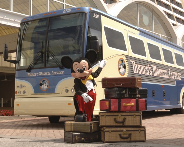 Mickey standing with suitcases next to Magical Express Bus